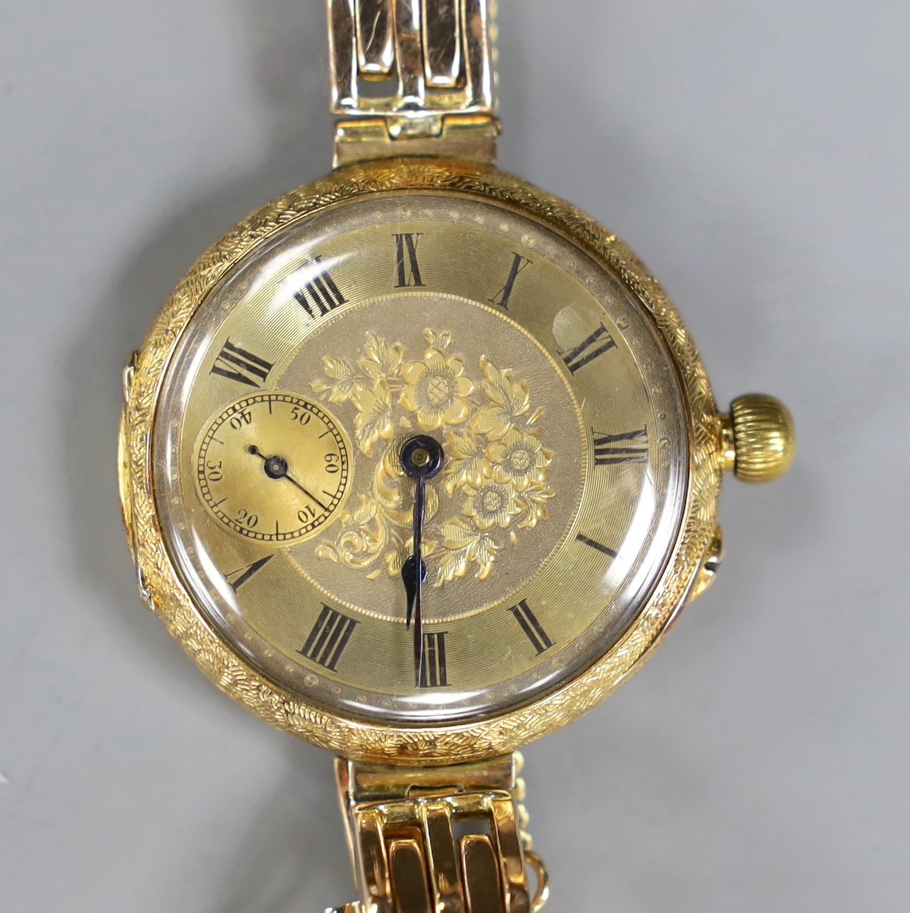 An early 20th century engraved 18ct gold fob watch, now converted to a wrist watch on a later expanding yellow metal bracelet
